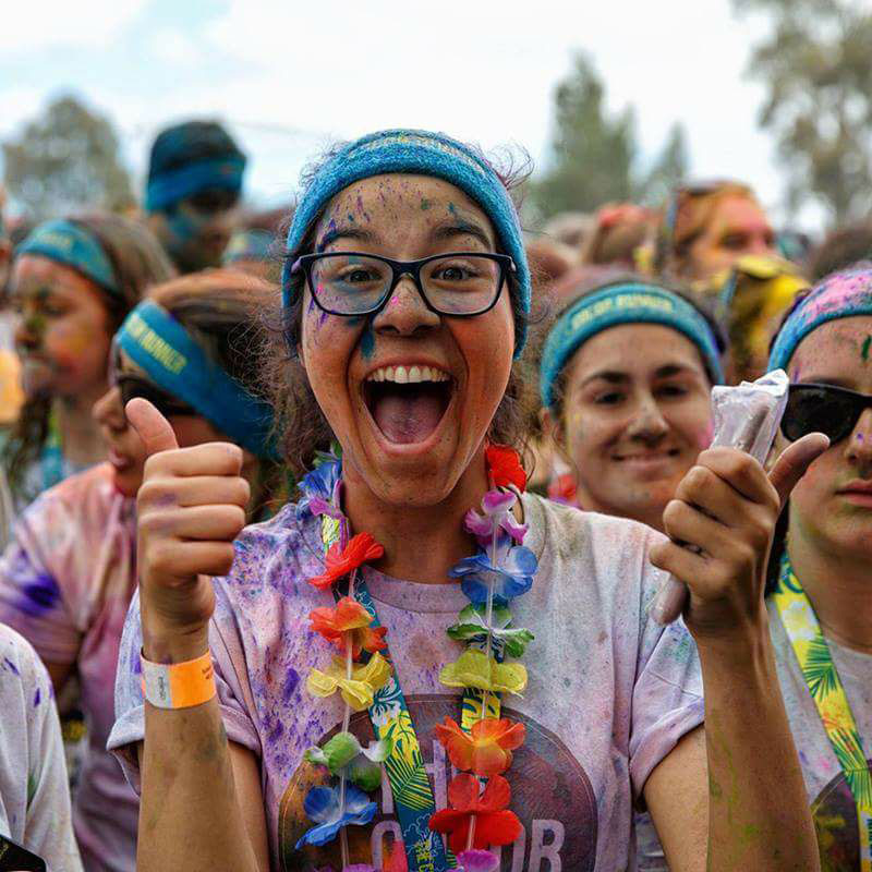 Young participant giving two thumbs up at a community color run